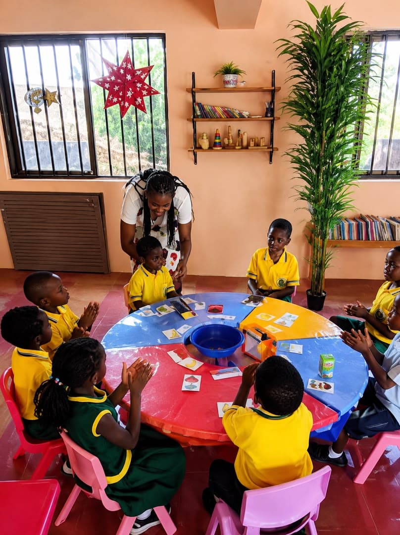 Preschool learners gathered around a round table for a teacher-led activity